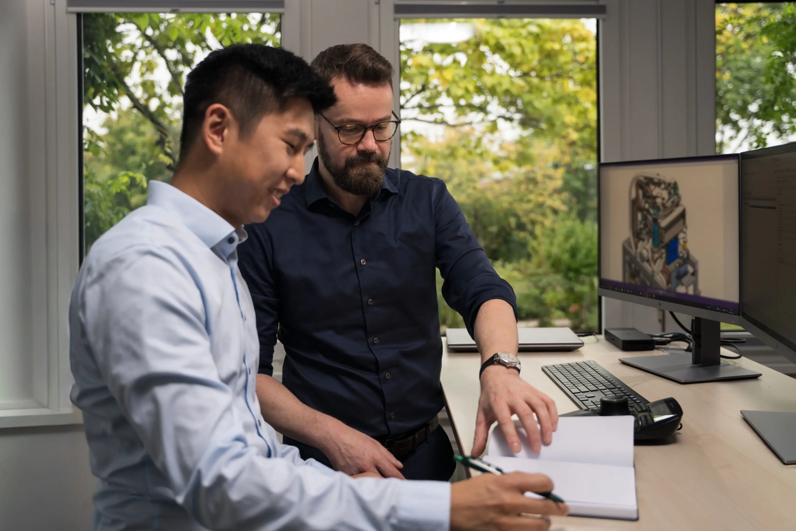 Two Male Employees Taking Notes at Desk